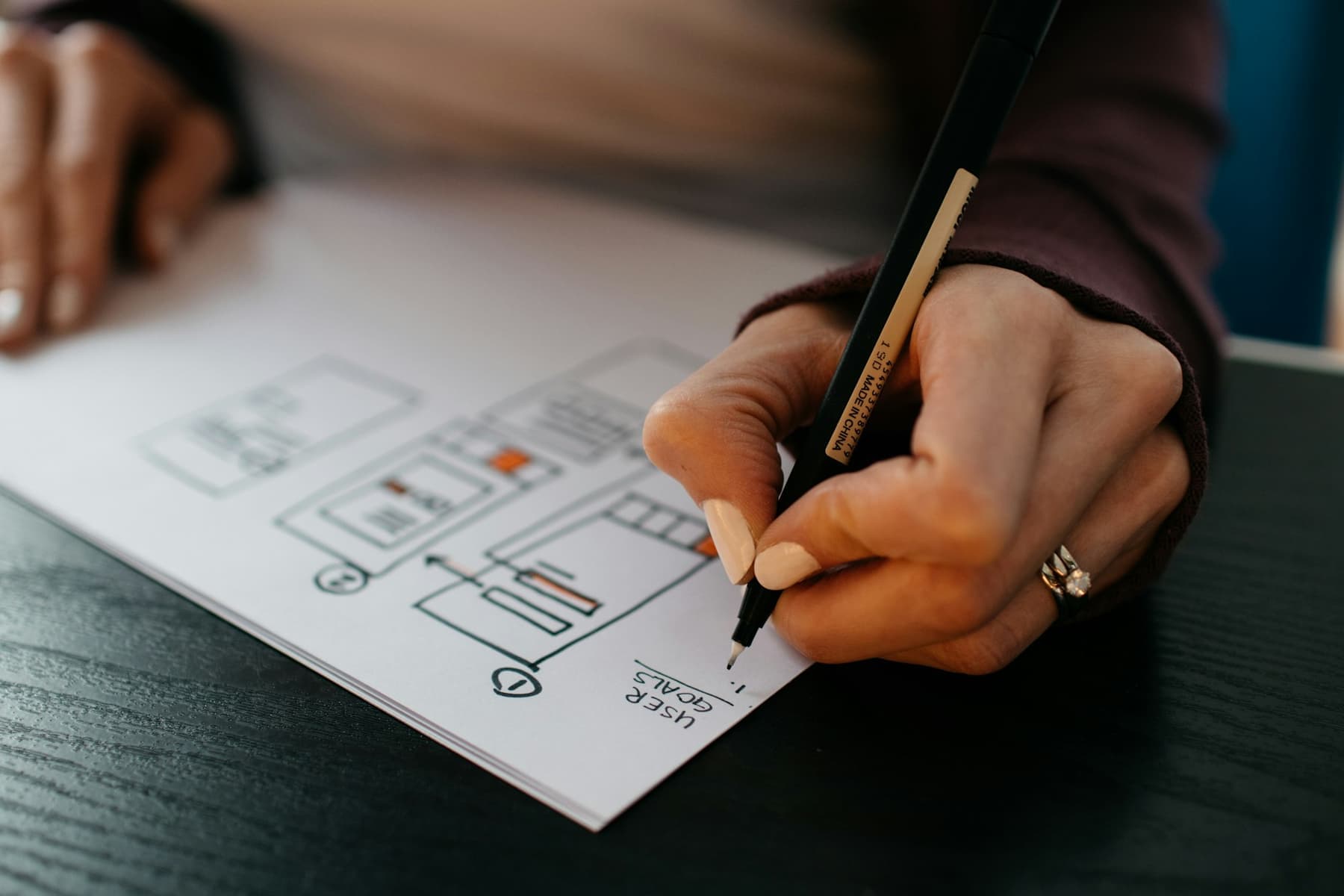 A hand sketching website wireframes on paper.