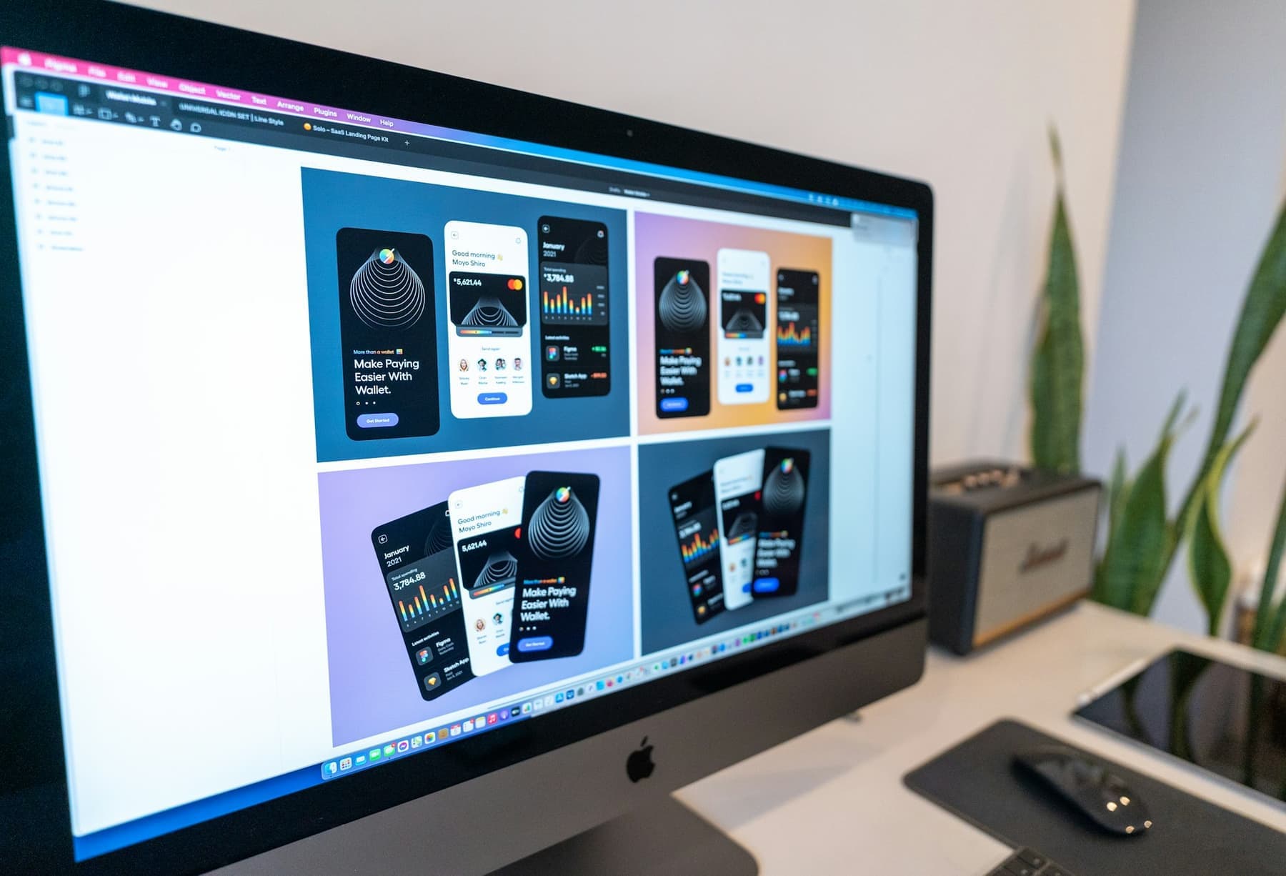 Mobile app screen designs displayed on a large monitor.
