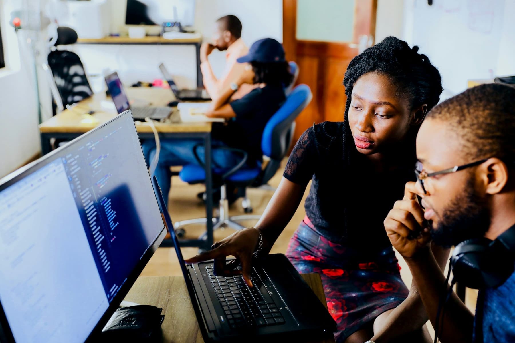 Two people reviewing work together on a laptop in an office.